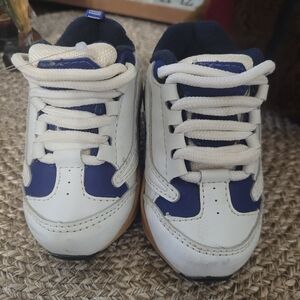 White and blue baby sneakers with laces and a caramel-colored rubber sole.